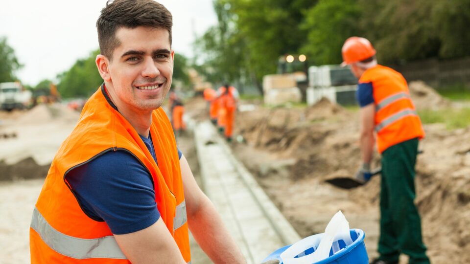 Smiling building worker holding helmet in hand
