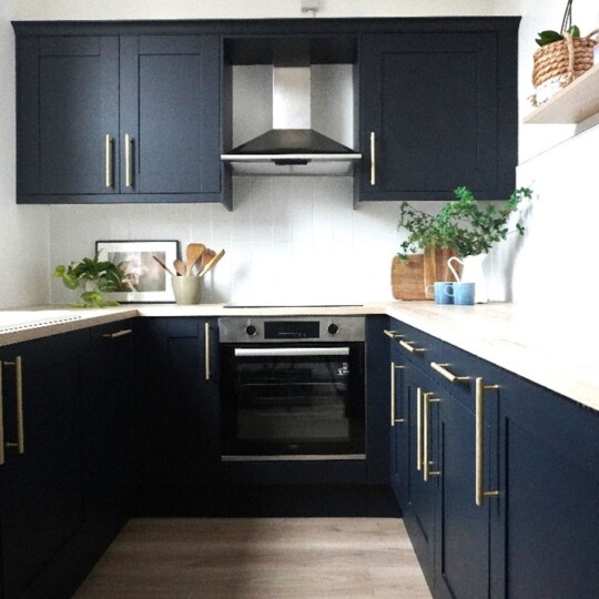 After photo of the renovated kitchen at 4 The Mount, Rothwell, featuring navy cabinetry with brass handles, modern appliances, and a bright contemporary design by Roberts Renovations Ltd.