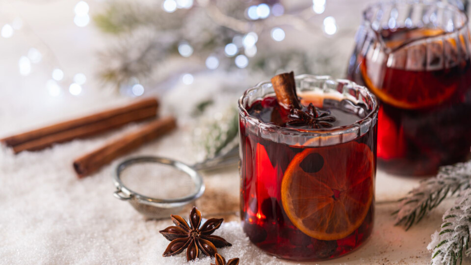 Cozy atmosphere with glass of Mulled wine, Christmas winter alcohol drink decorated by snow and christmas lights