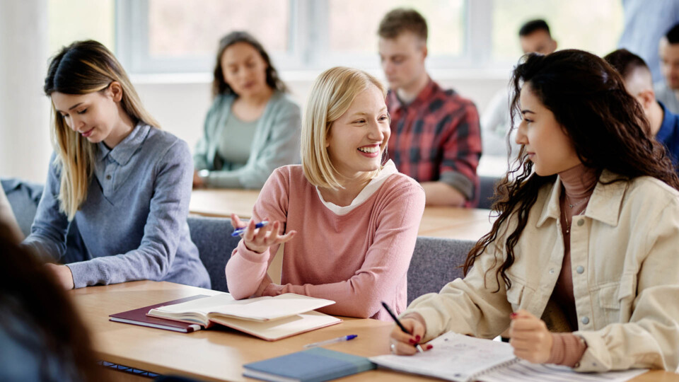 Happy female students talk while attending lecture at the university.